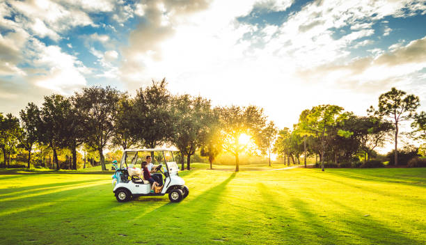 Father and daughter drive golf cart on scenic idyllic golf course playing a round of golf with active family stock photo