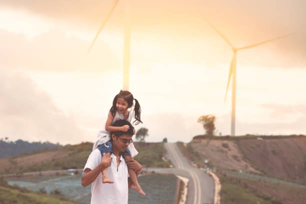 Father and daughter having fun to play together in wind turbine field Father and daughter having fun to play together in wind turbine field and child girl riding on father's shoulders in cloudy day in vintage color tone sustainable energy photos stock pictures, royalty-free photos & images