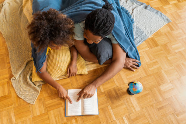 Father and daughter reading a book together at home. stock photo