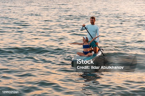 istock Father and daughter surfing on a sup board. Sea at the background. Summer vacations 1399321261