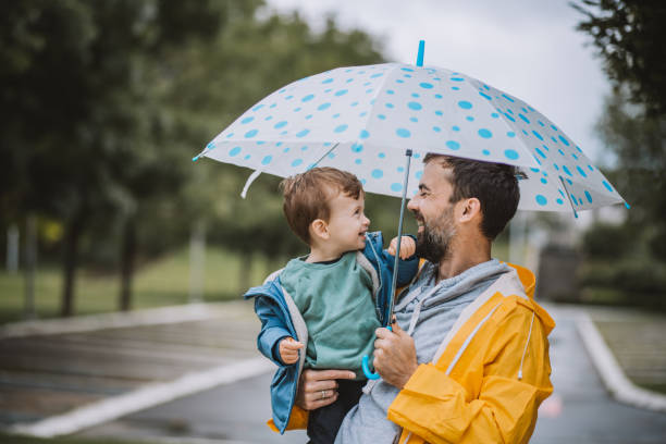 Father and son day Father and son having fun on rainy day. umbrella stock pictures, royalty-free photos & images
