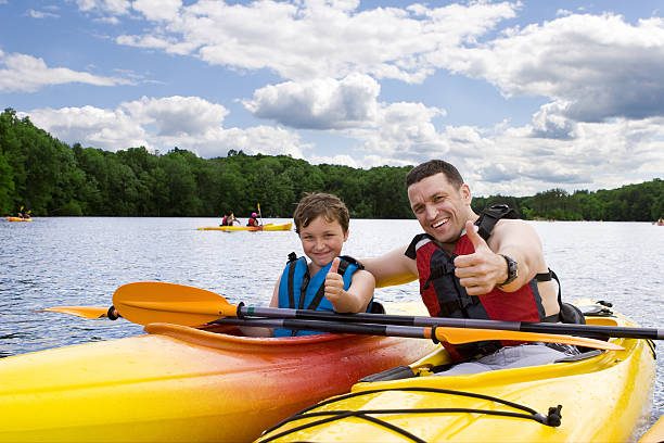 father and son enjoying kayaking - kajak stockfoto's en -beelden