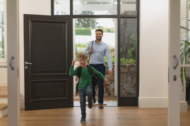 Father and son entering in a comfortable home Front view of Caucasian father and son entering in a comfortable home in front of stock pictures, royalty-free photos & images