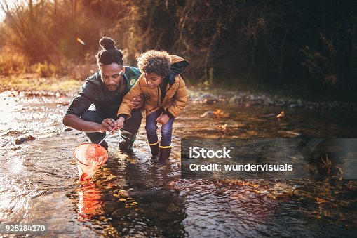 istock Father and son fishing with fishing net in river 925284270