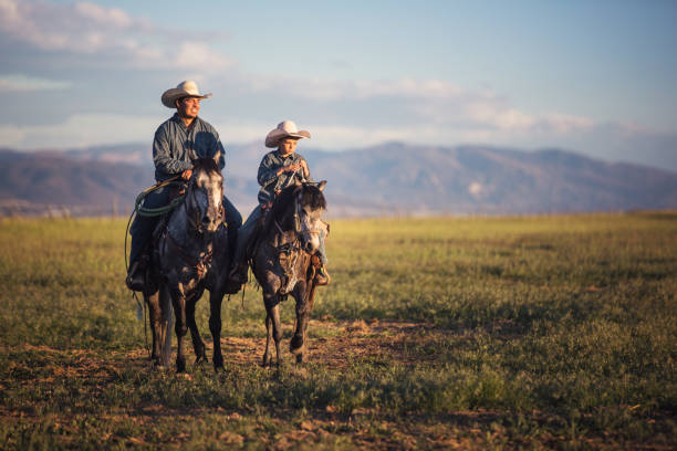 Father and son horseback riding Father and son horseback riding rancher stock pictures, royalty-free photos & images