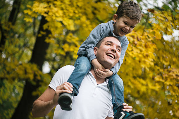 father and son in a park - piggyback funny stockfoto's en -beelden