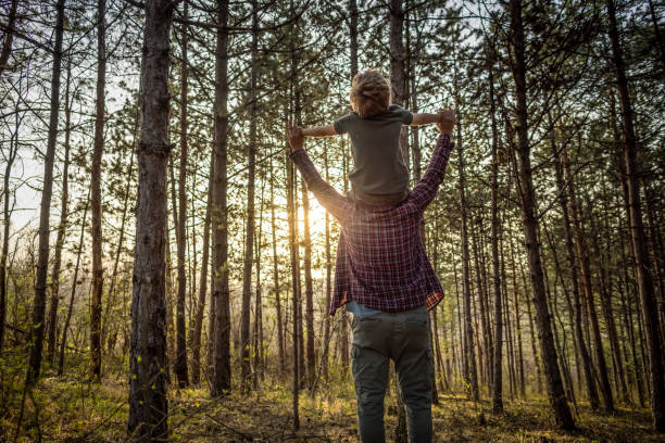 Father and son in nature Photo of father and son spending spring day in nature, boy and his father enjoying in nature together while father carrying him on a shoulders. fathers day stock pictures, royalty-free photos & images