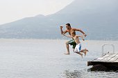 Father and son jumping from dock