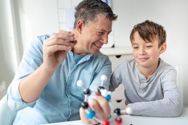 Father and son playing with atoms model, learning chemistry. Father is helping his son. stock photo