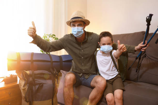 Father and son prepared for adventure at home with mask Father and son prepared for adventure at home with backpacks and protected with face mask with thumb up scout camp stock pictures, royalty-free photos & images