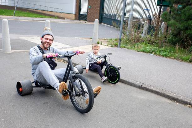 Father and son riding drift trikes Watford, Hertfordshire, England, UK - August 23rd 2020: Father and son riding drift trikes adult tricycle stock pictures, royalty-free photos & images