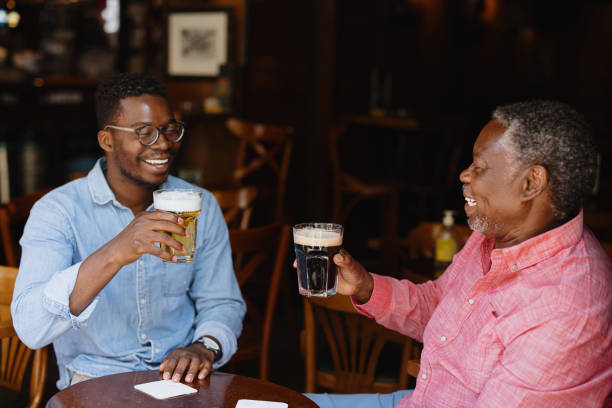 Father and son toasting and drinking beer in the pub stock photo