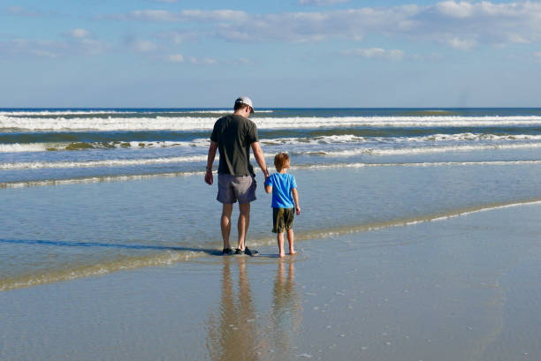 Father and son walking on the beach stock photo