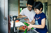 父と息子が台所の流しで新鮮な果物を洗う