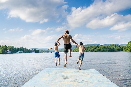 Father And Sons Jumping In Lake Stock Photo - Download Image Now - iStock