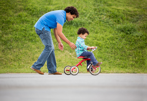 Father assisting his son in riding a tricycle