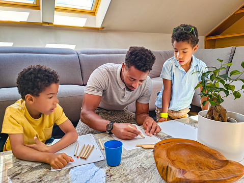 Father Colouring With His Two Young Children In The Living Room