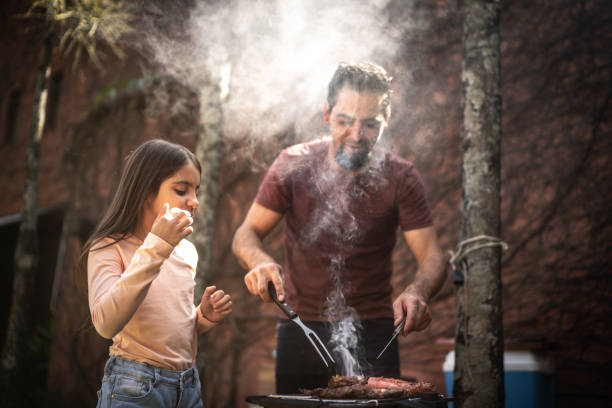 Father cutting a slice of meat to his daughter during a barbecue Father cutting a slice of meat to his daughter during a barbecue hot latino girl stock pictures, royalty-free photos & images