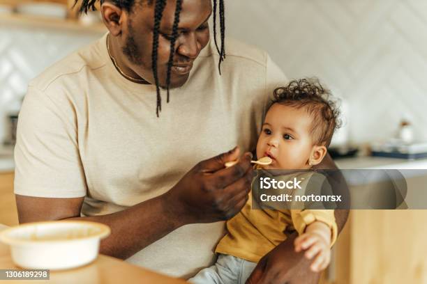 Father feeding cute baby girl, close-up, portrait.