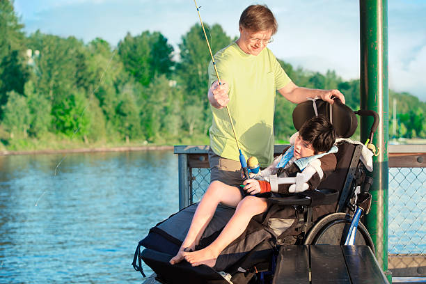 Father fishing off pier with disabled son in wheelchair stock photo