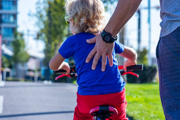 Father helping son ride a bike stock photo