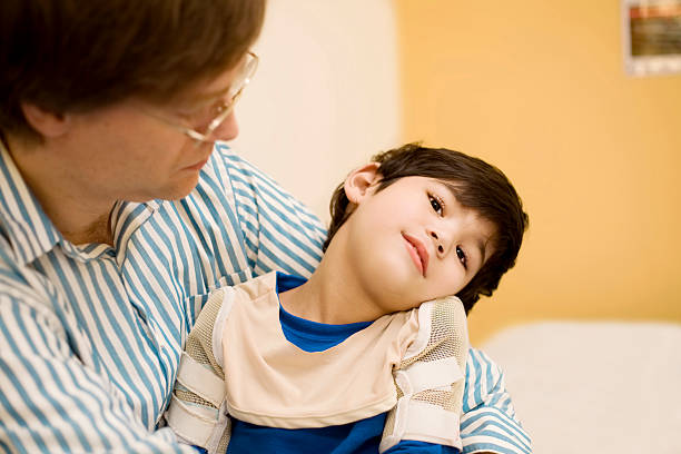 Father holding disabled son in doctor's office stock photo