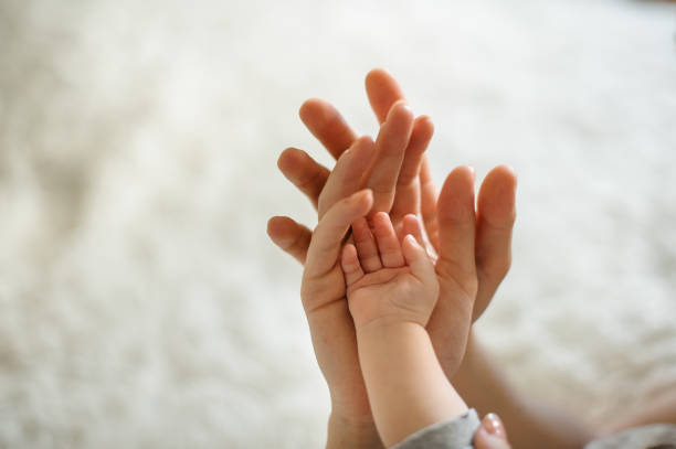 Father holding hands of his wife and their little cute daughter Father holding hand of his wife and their cute little daughter on the background of cozy counterpane in their home obscured face stock pictures, royalty-free photos & images