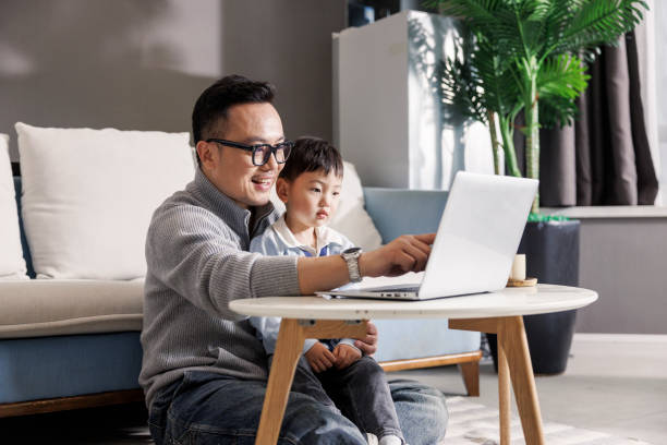 Father holding son working on laptop stock photo