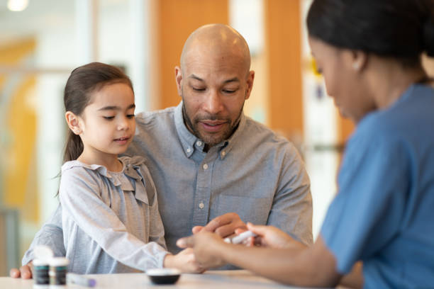 Father Holding Young Daughter At A Doctors Appointment An African American father is holding his young daughter at a medical clinic as an ethnic female doctor teaches them about diabetes and how to use an insulin pen. They are seated at a table across from the medical professional. allergy test stock pictures, royalty-free photos & images