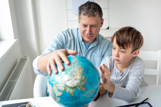 Father learns with child concept. Father and son get to know the world using a globe. stock photo