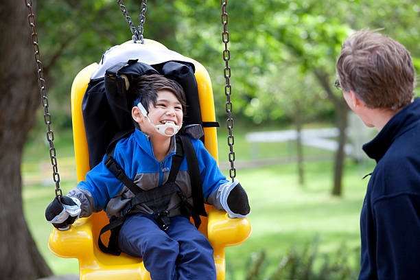 Father pushing disabled son  on handicap swing stock photo