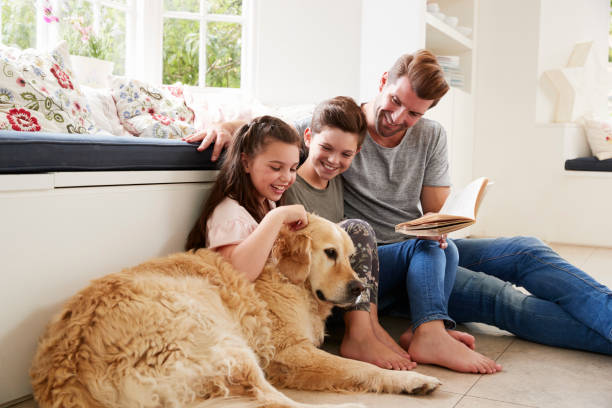 vader leesboek met zoon en dochter en huisdier hond thuis - hondachtige stockfoto's en -beelden