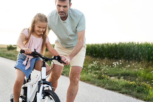 Father teaching his little daughter how to ride a bike