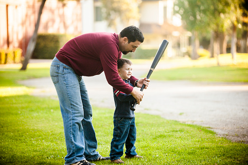 Father Teaching His Son How To Swing Baseball Bat Stock