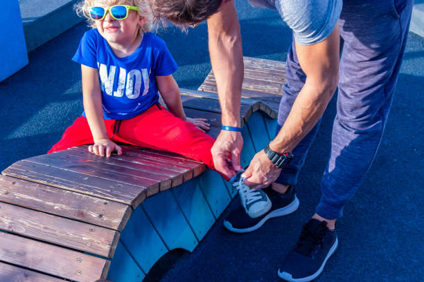 Father tying son's shoelaces stock photo