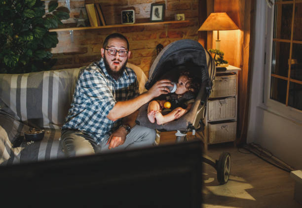 father watching tv with his young baby  boy stock photo