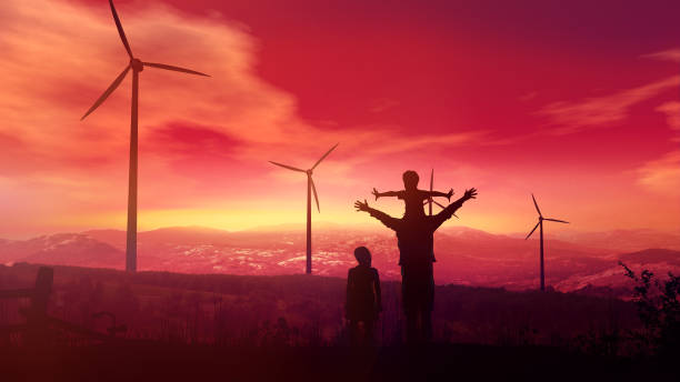 Father with children watching wind power plants at sunset stock photo