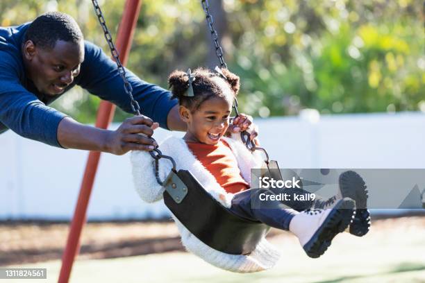 Father with daughter on playground swing