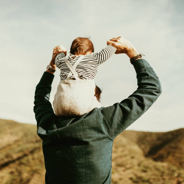 Father with his baby son in his shoulders in nature, looking at landscape. stock photo