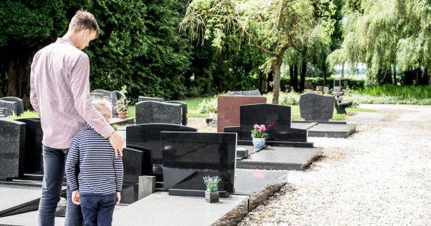 father with kid visiting grave stock photo