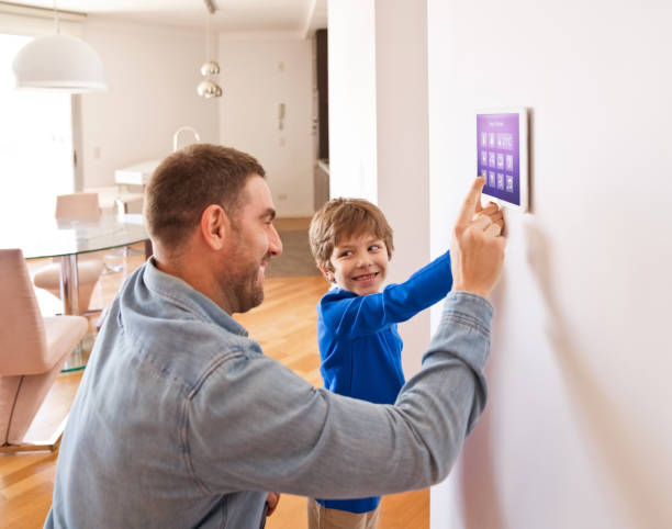 Father with son controlling smart devices with a digital tablet at home Father teaching his son controlling home with a digital touch screen panel. Concept of internet of things. smart thermostat stock pictures, royalty-free photos & images