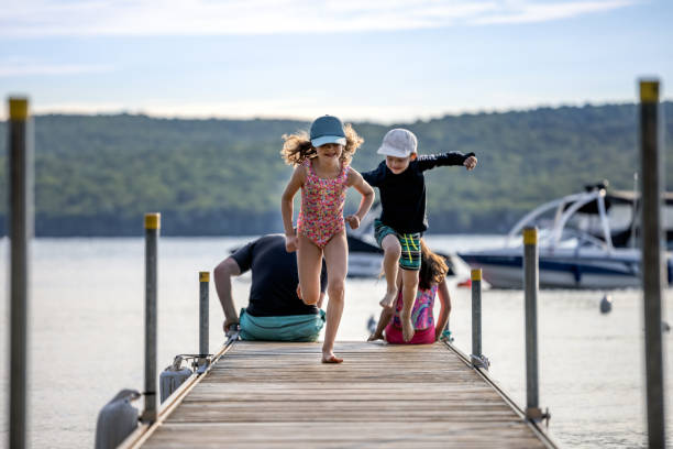 Father with Three Kids Sitting on Pier at the Lake During Summer Vacations, Quebec, Canada stock photo