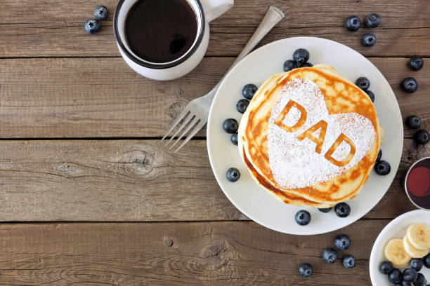 Fathers Day pancake breakfast with heart shape and DAD letters, above view corner border on rustic wood Pancakes with heart shape and DAD letters. Fathers Day breakfast concept. Above view corner border on a rustic wood background. father's day stock pictures, royalty-free photos & images