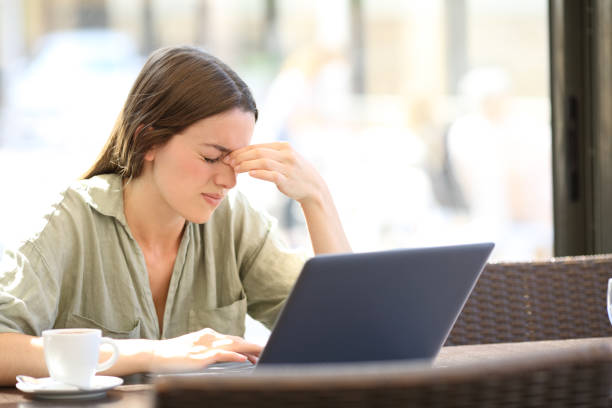 Fatigued woman suffering eyestrain in a coffee shop Fatigued woman suffering eyestrain working with a laprop sitting in a coffee shop headache stock pictures, royalty-free photos & images