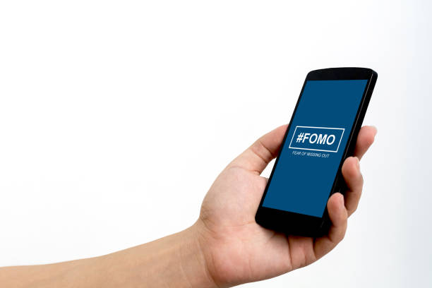 FOMO, fear of missing out concept. Male hand holding smartphone FOMO, fear of missing out concept. Male hand holding smartphone fomo stock pictures, royalty-free photos & images