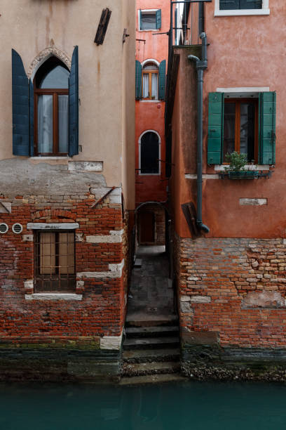 VENICE, ITALY February 16 , 2020.Picturesque Venice's red buildings with green windows near at canal stock photo