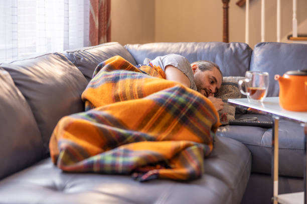 Feeling bad. A mature man is ill, he is sleeping on a couch under a warm plaid. stock photo