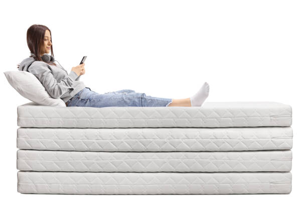 adolescente feemale en un montón de colchones usando un teléfono inteligente - type of mattresses for sleeping fotografías e imágenes de stock
