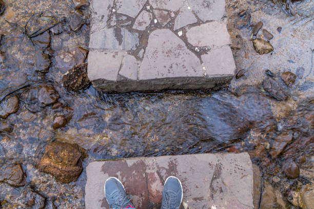 Feet crossing river on rocks stock photo