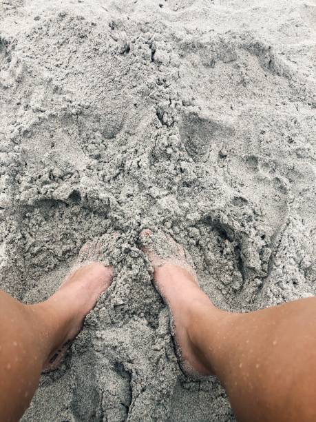 Feet in the sand at the beach Feet in the sand at the beach human feet buried in sand. summer beach stock pictures, royalty-free photos & images